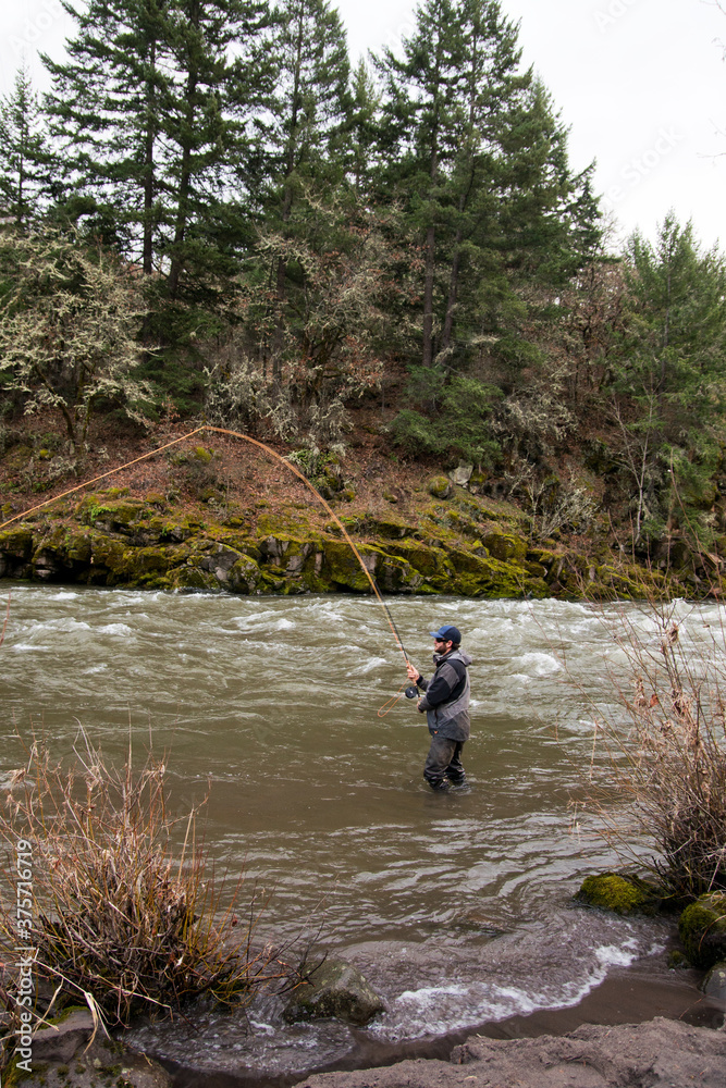 Man stands in the river casting an orange fly fishing line. Man stands in the river casting an orange fly fishing line.