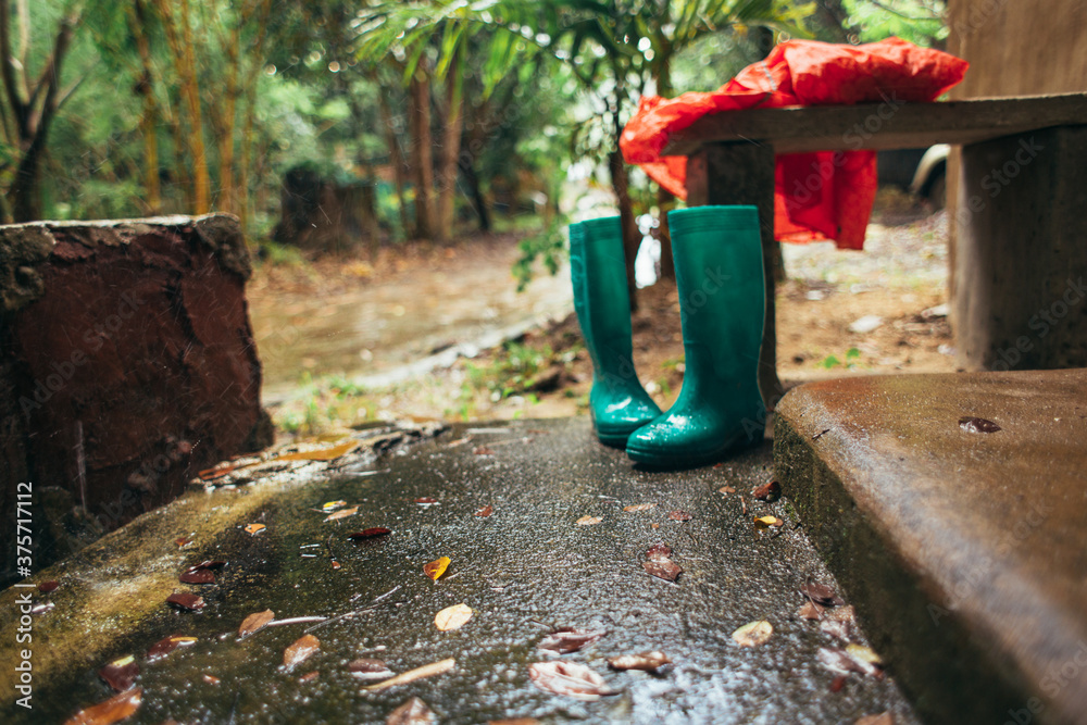 Green gumboots and red rain coat during rainfall Green gumboots and red rain coat during rainfall