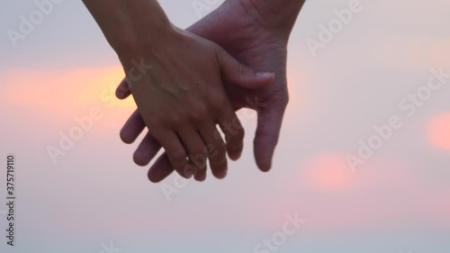 Close-up of hands disconnected from sunlight flare in background. A beautiful romantic moment between two lovers ends with a breakup. Mature relationship. Psychology of relations. Divorce of a couple