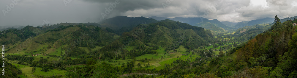 Moody  landscape of mountains and green valley and forest with trees with a beautiful dark sky with clouds in Salento, Colombia