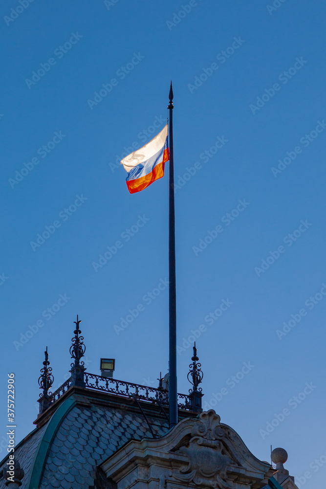 The flag of Russia flies on the roof of an ancient castle against a blue sky