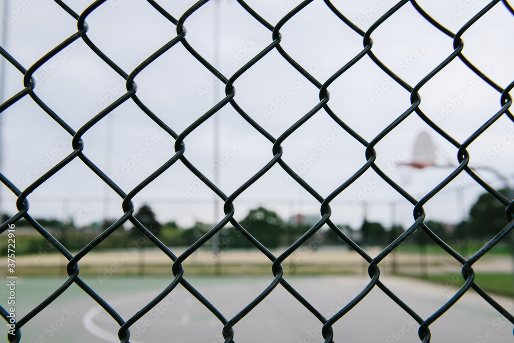 Looking through chain link fence to public basketball court Looking through chain link fence to public basketball court