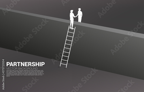 Silhouette of businessman handshake from across the wall. Concept of team work partnership and success agreement.