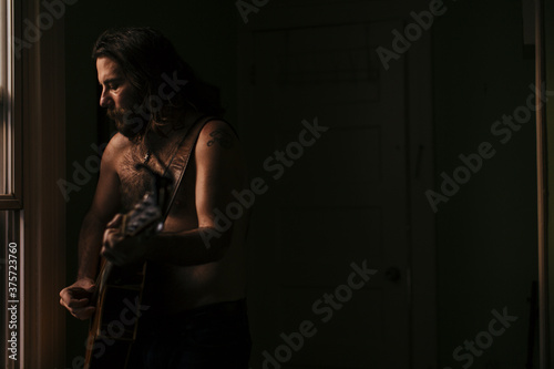 A musician plays his soulful guitar by his apartment window photo