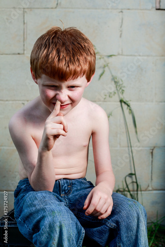 Young redheaded boy picking nose with shirt off photo