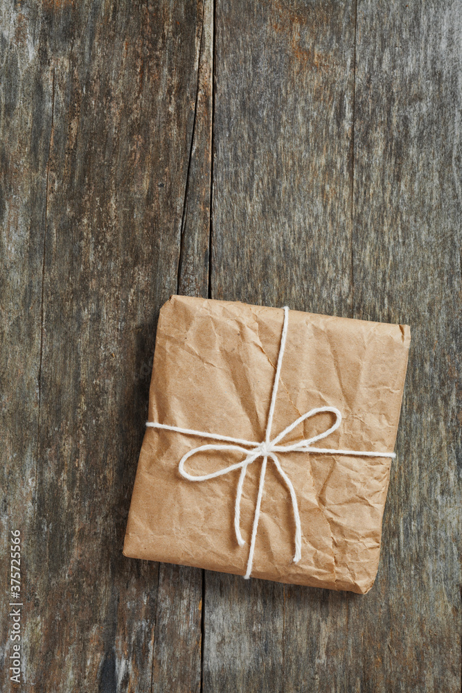 Package wrapped in wrinkled brown paper lying on weathered wood Package wrapped in wrinkled brown paper lying on weathered wood