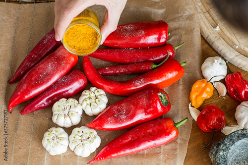 Hand sprinkling turmeric on peppers and garlic