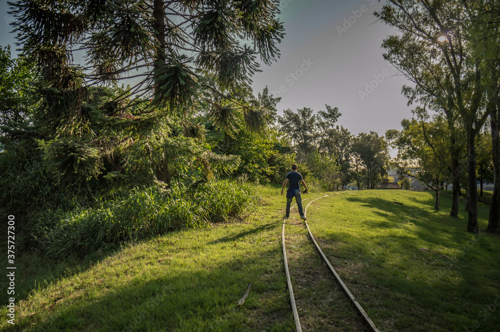 Unrecognizable young man walks on the abandoned train tracks