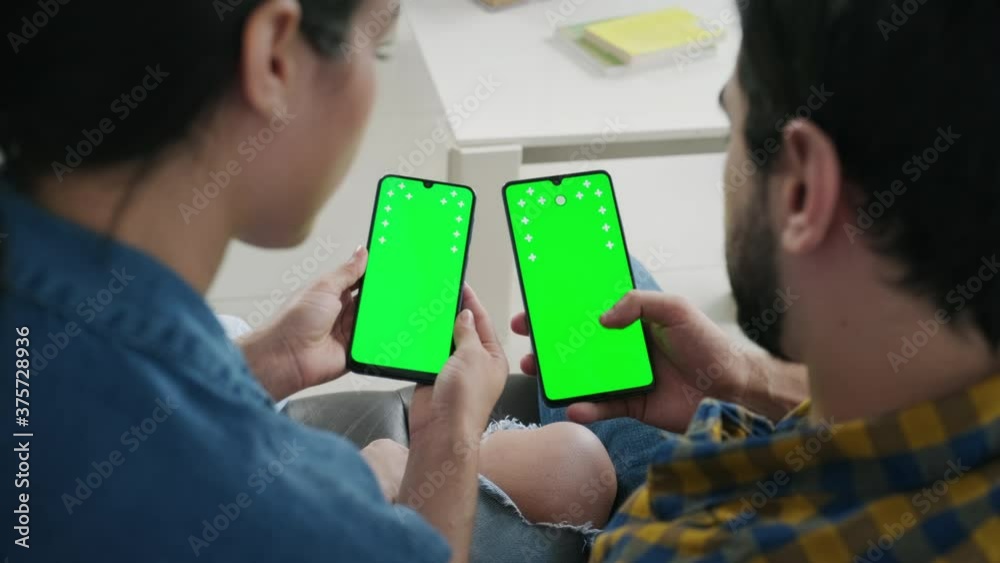 Young people using cell phones with green screen for internet and social media. Man and woman holding smartphones for web site. Boyfriend and girlfriend watching movie and photos on mobile telephones Young people using cell phones with green screen for internet and social media. Man and woman holding smartphones for web site. Boyfriend and girlfriend watching movie and photos on mobile telephones