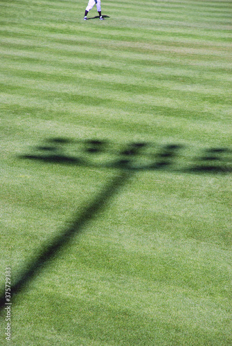 Shadow of baseball stadium lights on field with outfielder
