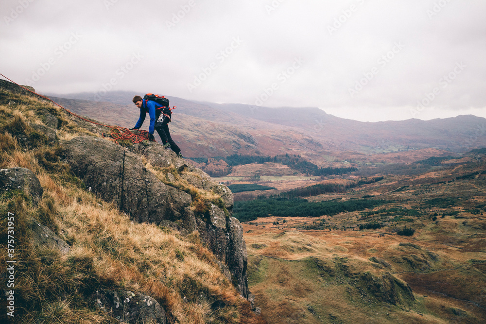Mountaineer scrambles on edge of mountainside. Mountaineer scrambles on edge of mountainside.
