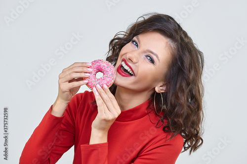 attractive girl in a red dress bites a doughnut