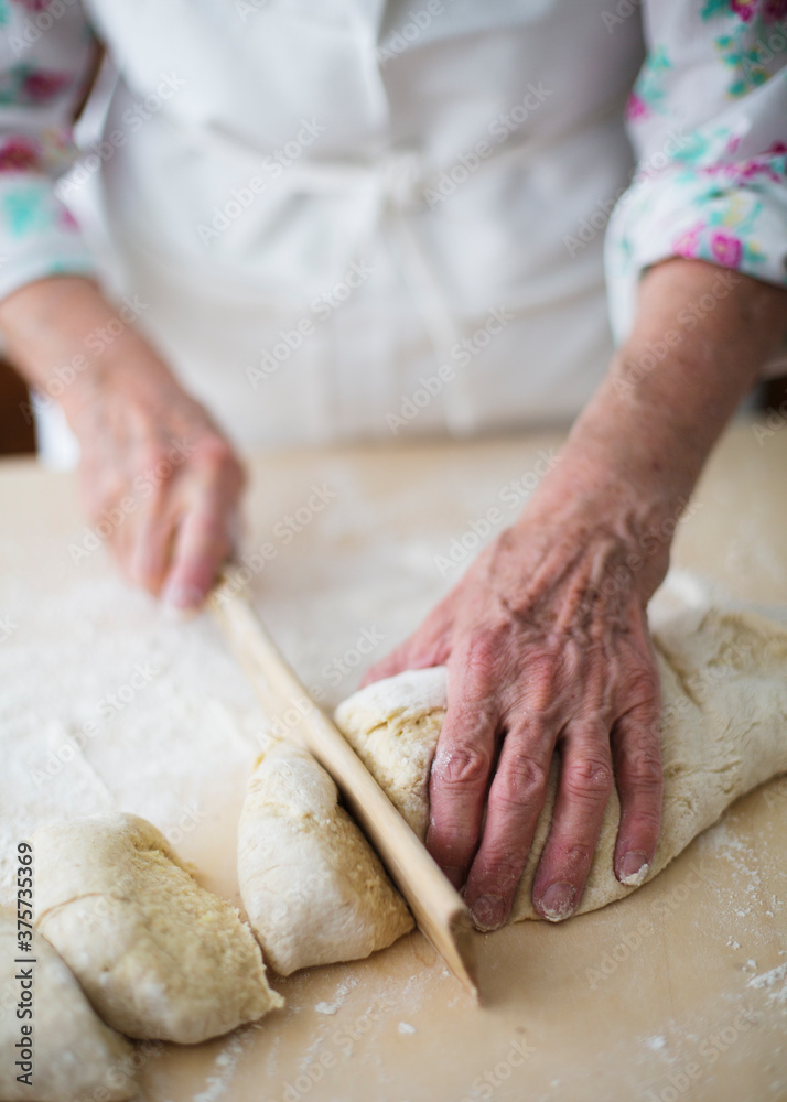Woman cutting pieces out of fresh homemade dough with wooden cutter Woman cutting pieces out of fresh homemade dough with wooden cutter