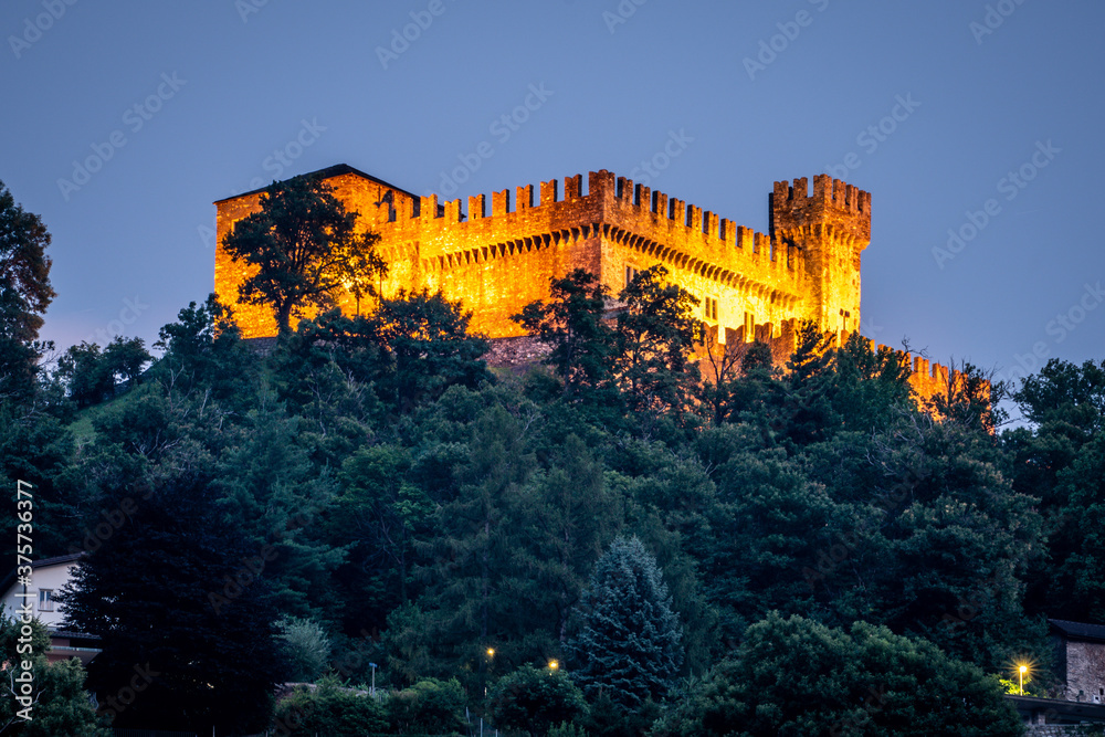 Distant view of Sasso Corbaro medieval castle illuminated at night in Bellinzona Switzerland