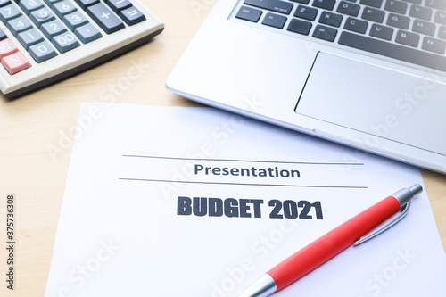 Budget concept.  White paper with Budget 2021 text with a laptop and calculator on wooden table 