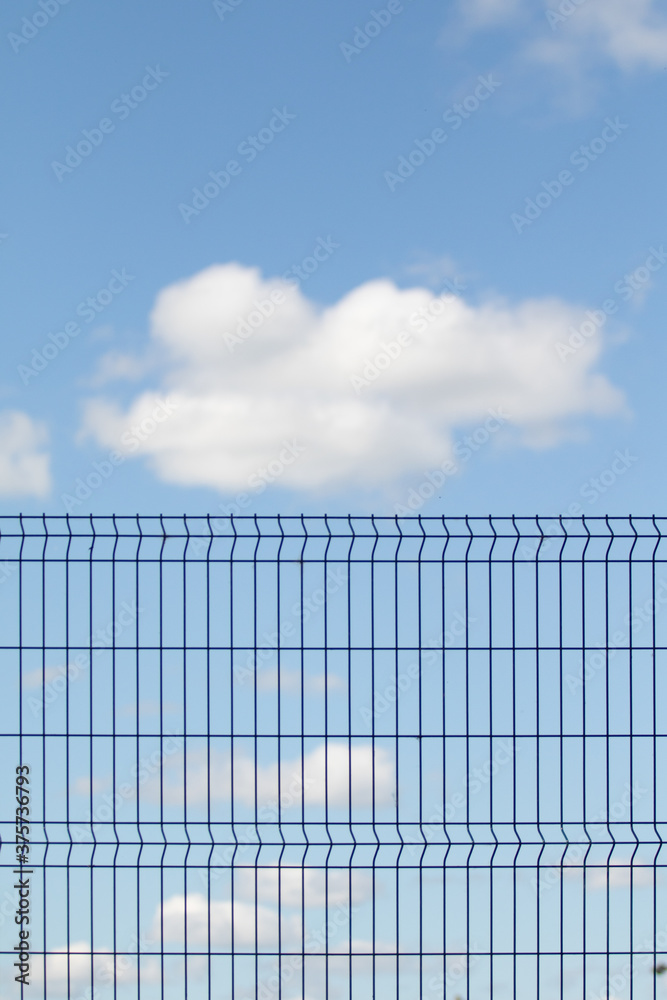 Metal grid against the blue sky with white clouds. Metal grid against the blue sky with white clouds.