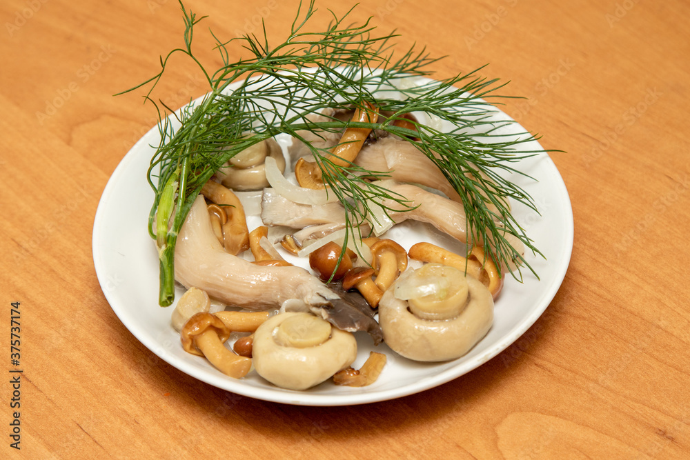 Pickled mushrooms in a plate on a wooden table.