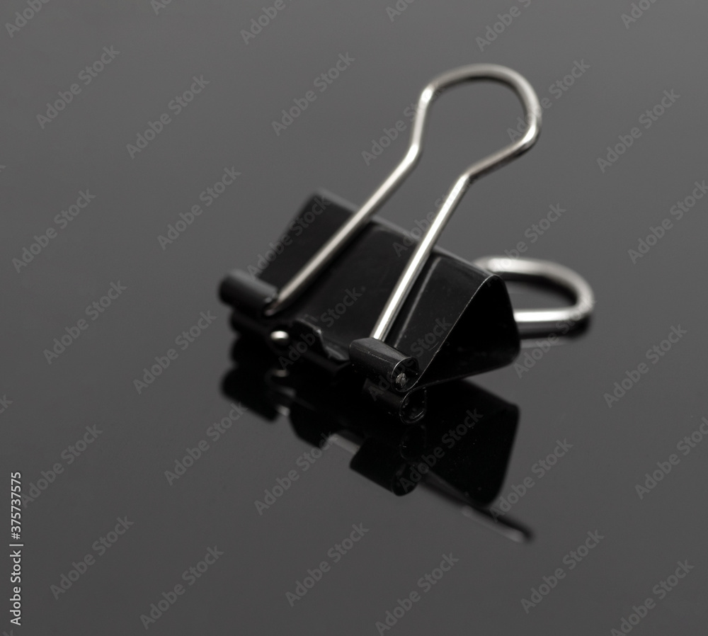 Black office clothespin isolated on a black background. Black office clothespin isolated on a black background.