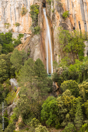 waterfall flowing from a hole in the wall of a mountain