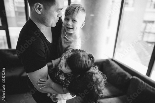 Young father having fun playing with three kids inside laughing photo