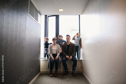 Young family of five sitting together in window sill - looking serious photo