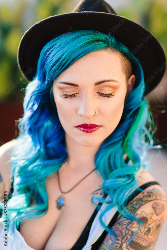 Vertical portrait of a beautiful mixed ethnicity women with blue dyed hair and a nose ring.