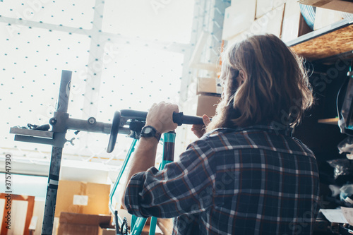 Young Mechanic With Long Hair Putting Handlebar of New Fixed Gear Bicycle photo