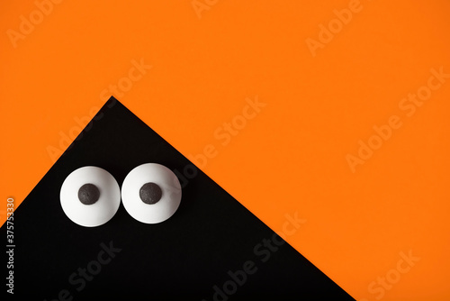 Halloween background, black ghost with bulging eyes on a orange