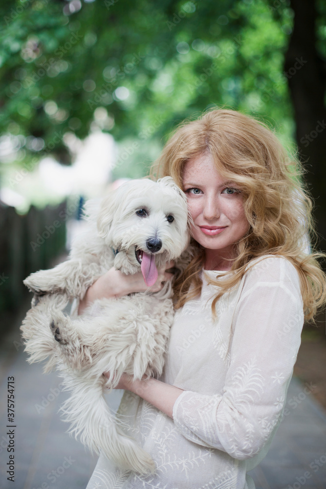 Young beautiful woman with freckles holding a little white puppy Young beautiful woman with freckles holding a little white puppy