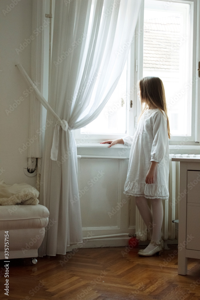 Little girl watching trough the window in her lovely room Little girl watching trough the window in her lovely room
