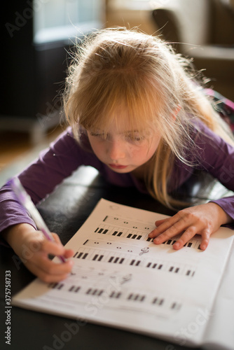 Little Girl Learning to Play Piano with Sheet Music photo