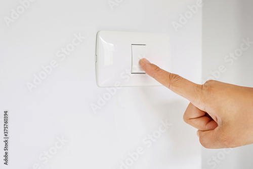 Fotografia Turn off the light, close up finger man hand is closing the power switch with wall at home  to save energy