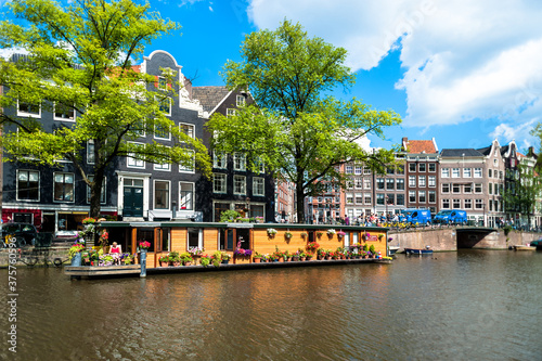 Beautiful houseboat on Amsterdam canal in summertime with sun and blue sky photo