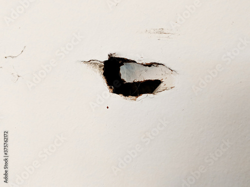 Hole in the Wall on White Dry Wall - Noticeable Damage in an Interesting Shape with Dark Contrast