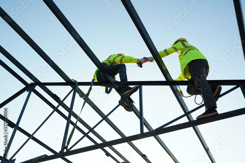 Construction workers wearing safety harness belt working at high place at building site. photo