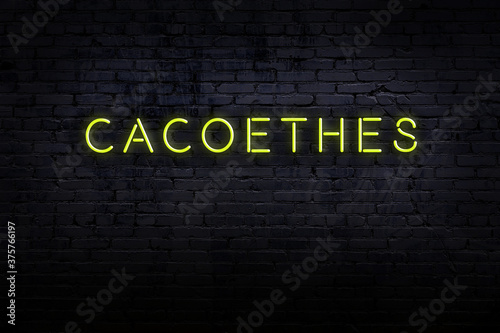 Neon sign. Word cacoethes against brick wall. Night view photo