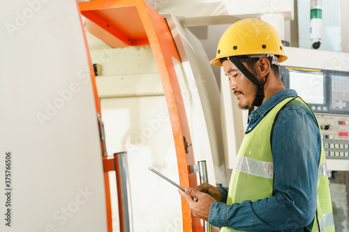 side view of man engineer working on machine and check with tablet digital in the factory