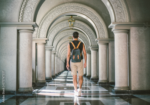 Young man walking through long hallway.