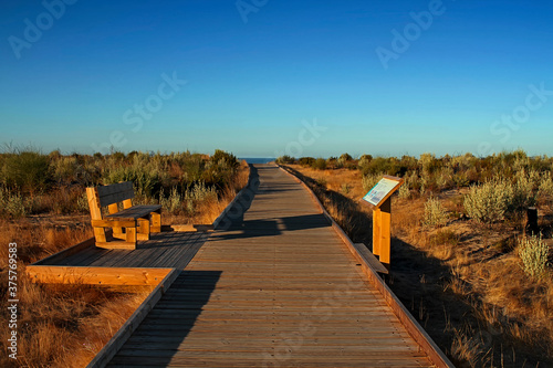 Wooden path on the sand in front of the sea in Cuesta Maneli photographed at sunrise, within the Doñana National Park, Huelva, Spain photo