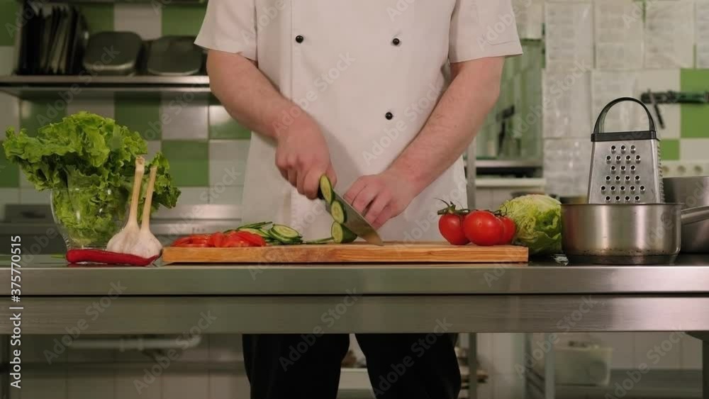 Close-up of a professional chef slicing a fresh cucumber on a cutting Board in a modern restaurant kitchen. Close-up of a professional chef slicing a fresh cucumber on a cutting Board in a modern restaurant kitchen.