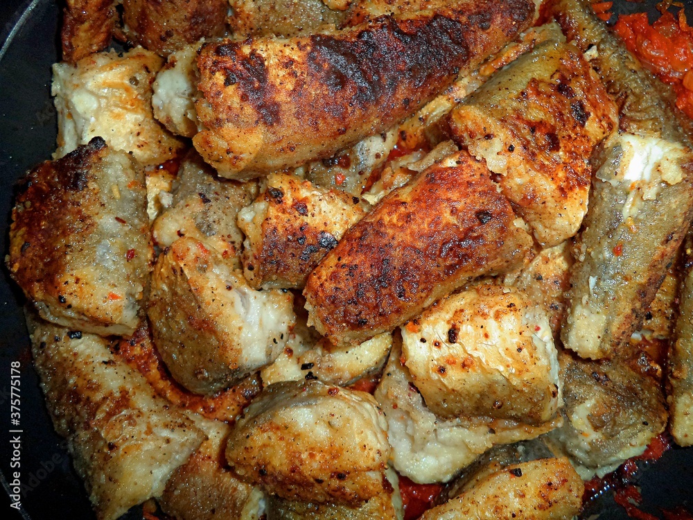 pieces of fried fish in a frying pan close up