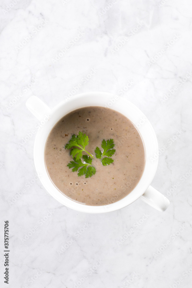 Champignon mushroom cream soup in white bowl on marble table. Top view Champignon mushroom cream soup in white bowl on marble table. Top view