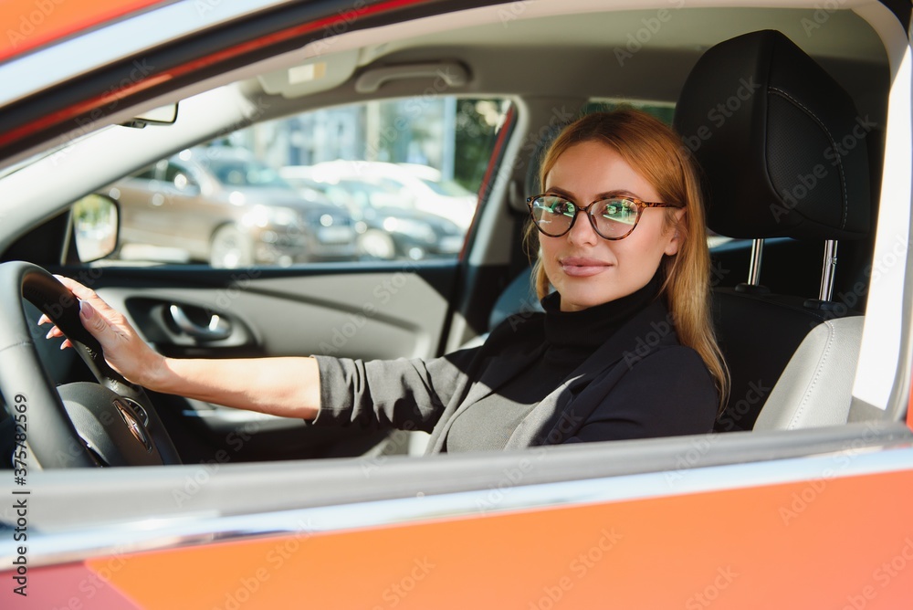 Beautiful mature woman in business suit driving a car to office. Businesswoman drive a car in city.