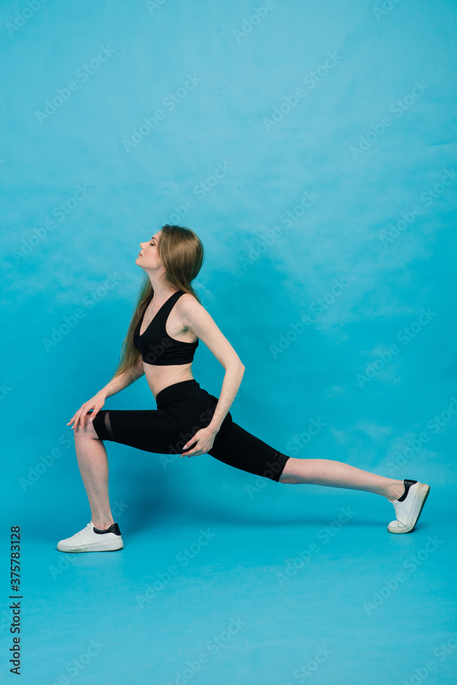Woman in sportswear stretching legs, warming up on blue background. Woman in sportswear stretching legs, warming up on blue background.