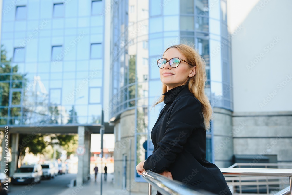 Portrait shot of the Caucasian beautiful woman office worker standing near big glass office center.