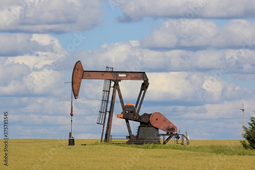 oil pump jack in the field with blue sky and white clouds in Kansas. photo