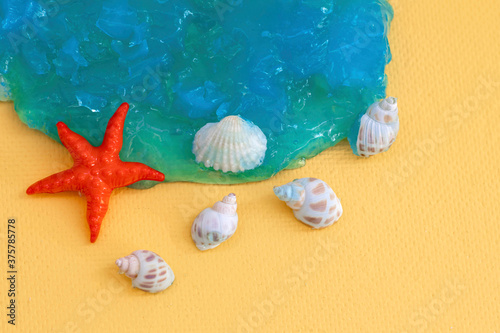 Starfish and seashells on a blue transparent texture. Yellow background, copy space. Decorative composition for design on the theme of the sea and relaxation. The photo
