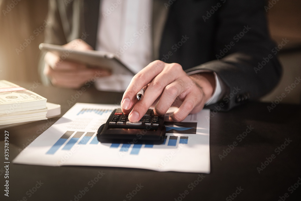 Businesswoman working with tablet and using a calculator to calculate the numbers of static in office. Finance accounting concept. Businesswoman working with tablet and using a calculator to calculate the numbers of static in office. Finance accounting concept.