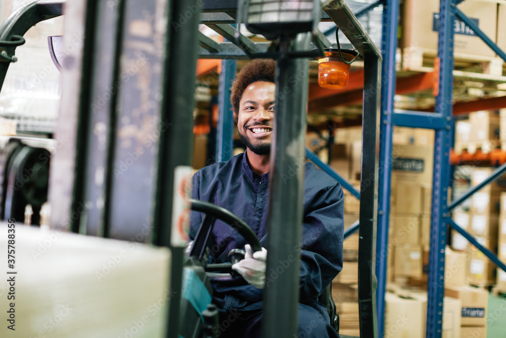 Young male worker driving a forklift in a warehouse. Young male worker driving a forklift in a warehouse.