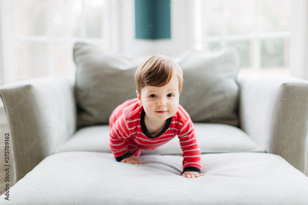 Adorable young boy crawling in a big chair